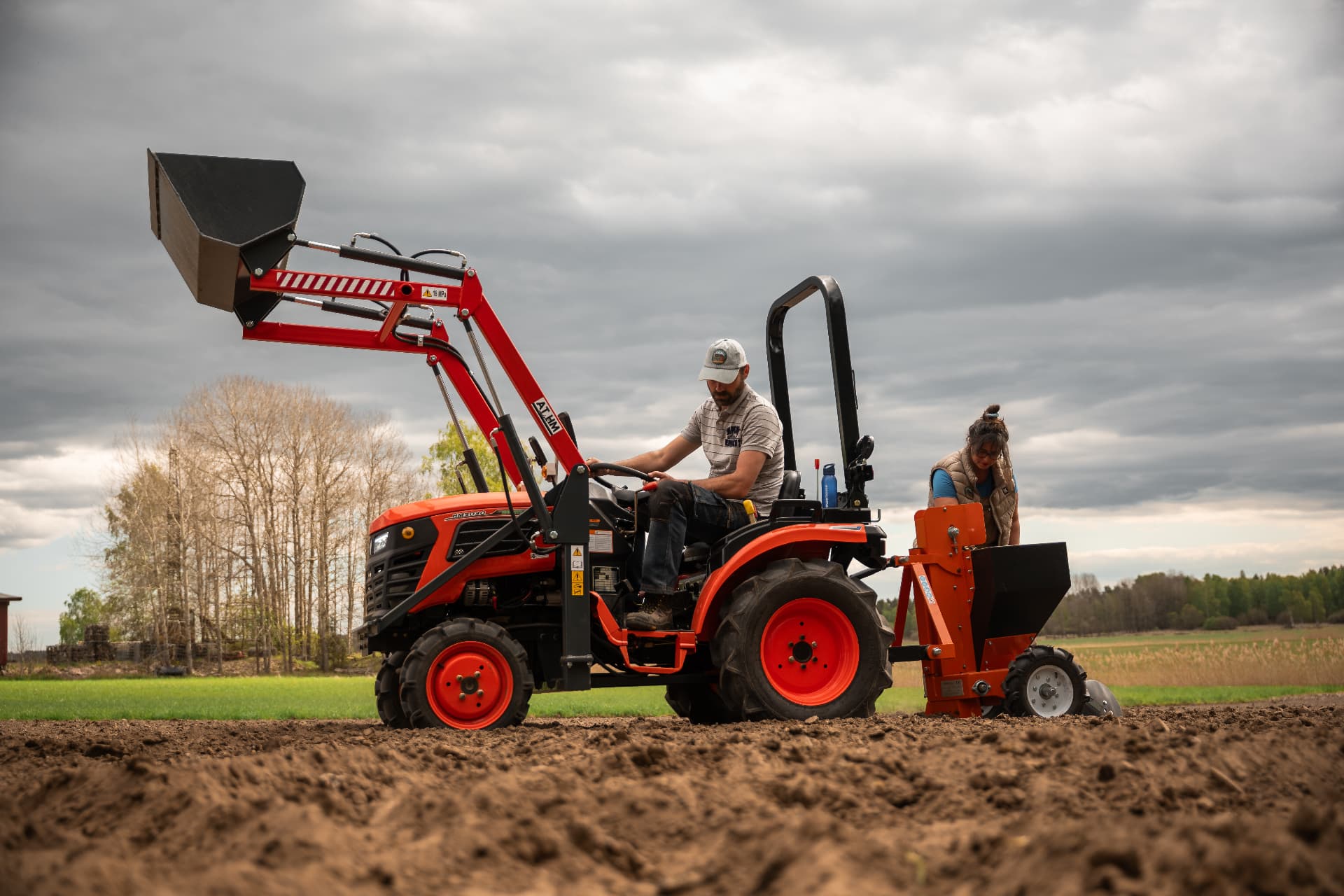 Två odlare som arbetar med traktor på åkern